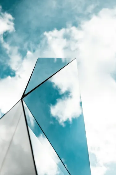 A cloudy sky with a triangular, mirrored object in the foreground.