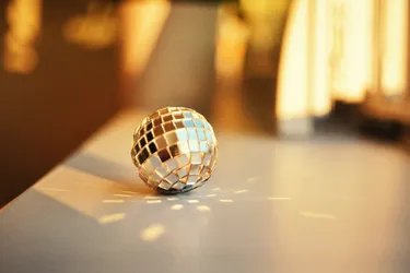 A small mirror ball reflecting light onto the table it is sitting on.