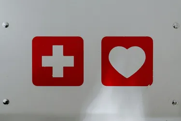 A white background with two red squares in the middle containing a white heart and cross.