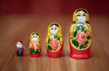 Four Babushka dolls in order from smallest to larges wearing face masks