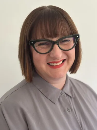 Head shot of Jessamy House wearing a white white with a purple pattern.