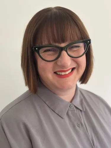 Head shot of Jessamy House wearing a white white with a purple pattern.