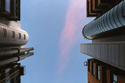 An view looking up at the sky as the sun sets surrounded by tall buildings.