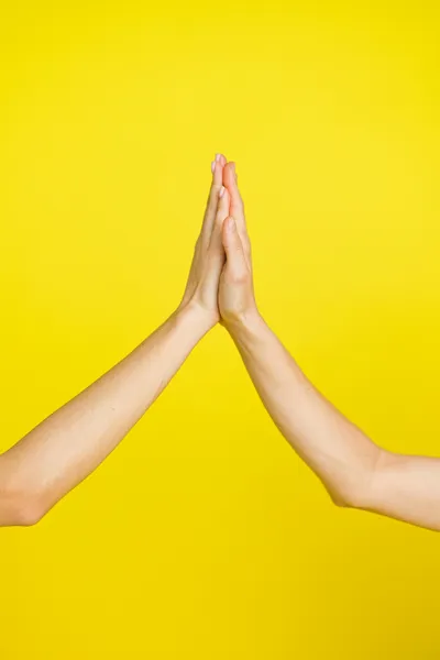 Two hands giving a high five with a yellow background.